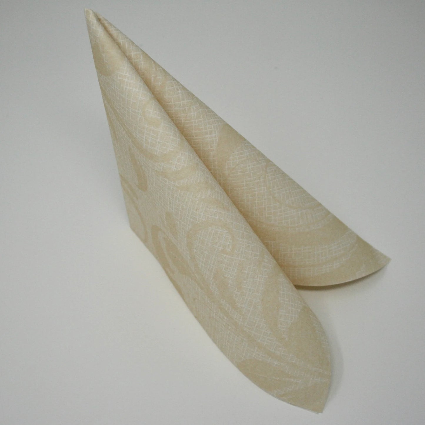 Romantische Airlaid-Serviette mit klassischem Ranken-Muster in Creme und Beige, stehend zum Dreieck gefaltet für die Tischdekoration