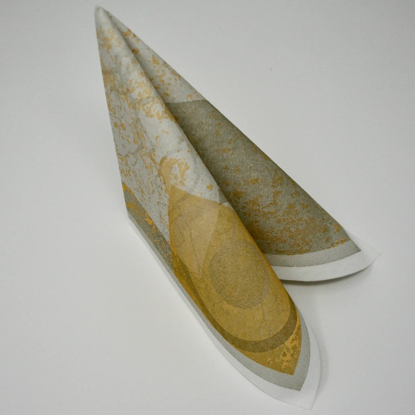 Moderne Airlaid-Serviette mit künstlerischem Muster in Taupe, Gold und Grau, stehend zum Dreieck gefaltet für die Tischdekoration